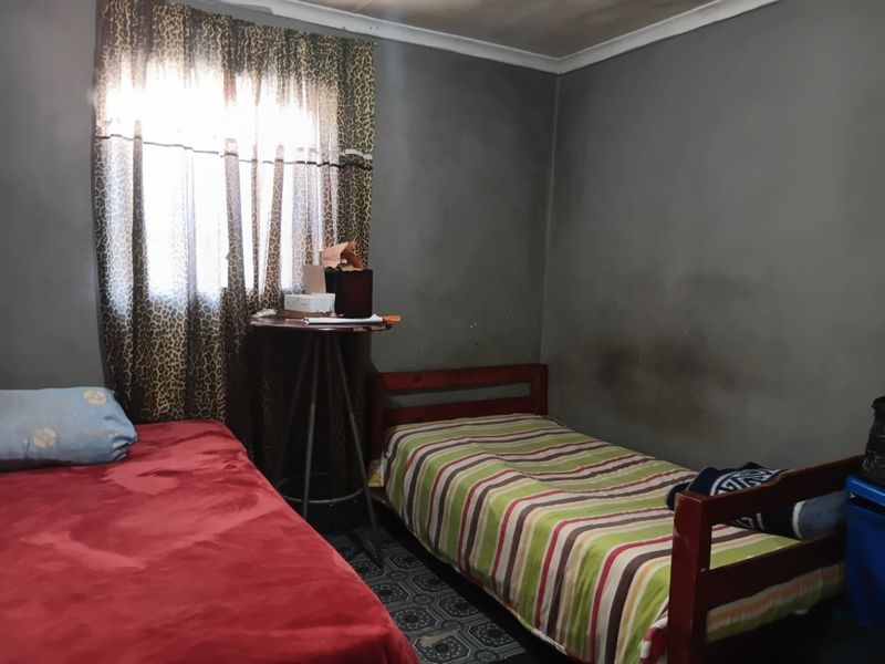 A bedroom featuring dark grey walls with visible staining and patterned floor tiles.