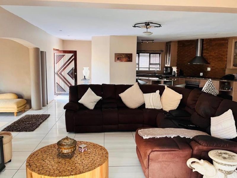 Spacious open-plan living area featuring tiled floors, a stone-accented kitchen with built-in cabinetry, and a seamless flow between the lounge and kitchen space.