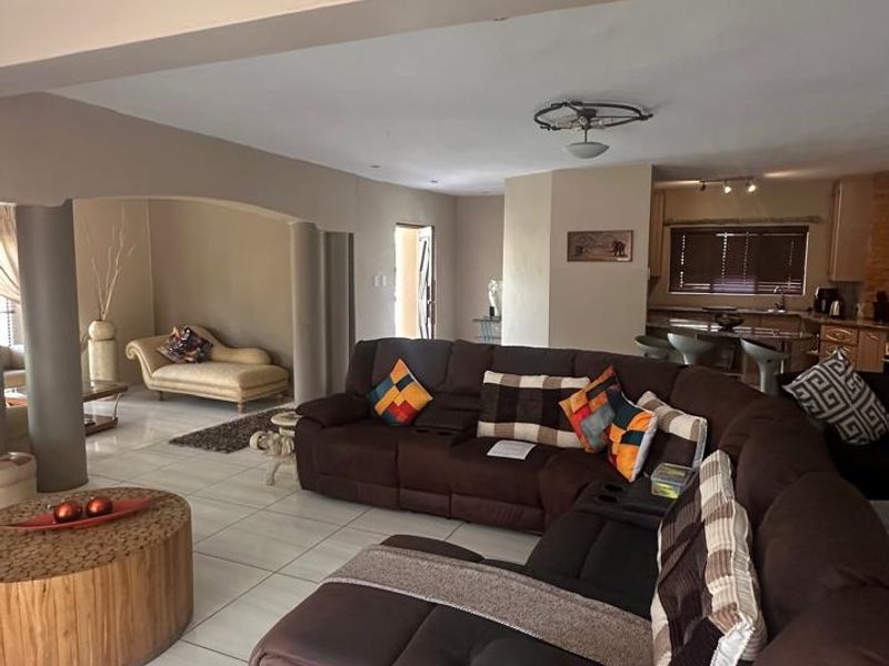 Spacious open-plan living area featuring tiled floors, structural columns, and an integrated kitchen with island, creating a versatile and connected home layout.