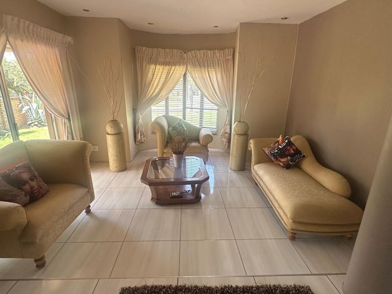 A bright and spacious living room featuring large windows, tiled flooring, and direct access to the outdoor area through a sliding glass door.