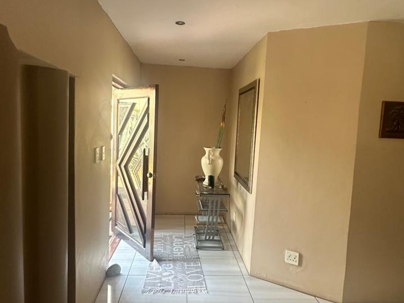 A bright entrance hall featuring neutral tiled flooring, recessed downlighting, and a solid wood front door leading into the home.