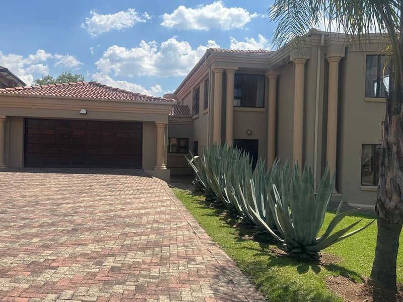 Front elevation of a substantial multi-story residence featuring a paved driveway, double garage, and architectural columns.