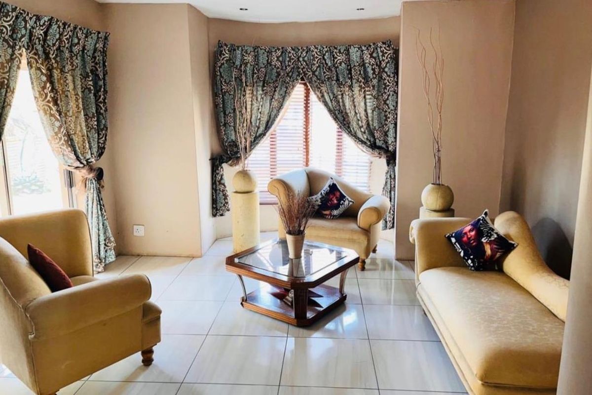 A comfortable living room featuring large format floor tiles and a bay window with venetian blinds, offering a bright and inviting space.