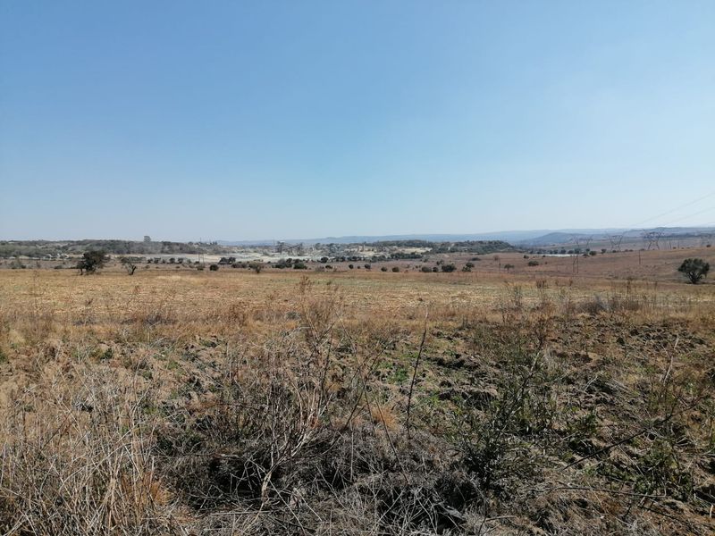 A wide-angle view of the expansive farm landscape featuring natural terrain and open fields under a clear sky.