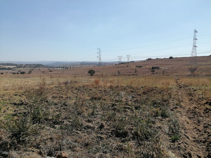 Expansive view of open farm land featuring prominent high-voltage transmission towers and power lines stretching across the horizon.