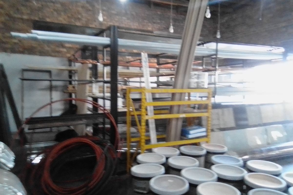 A commercial utility or storage space featuring exposed brick walls, industrial shelving units, and overhead lighting.