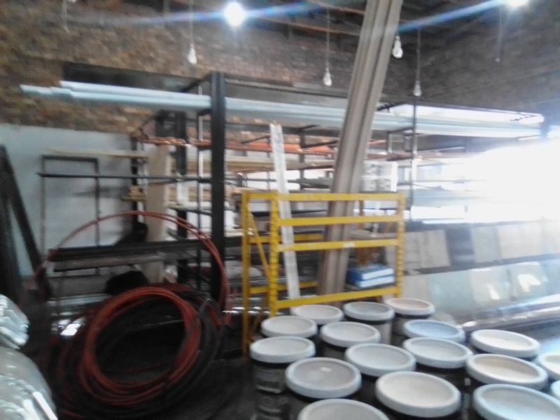 A commercial utility or storage space featuring exposed brick walls, industrial shelving units, and overhead lighting.