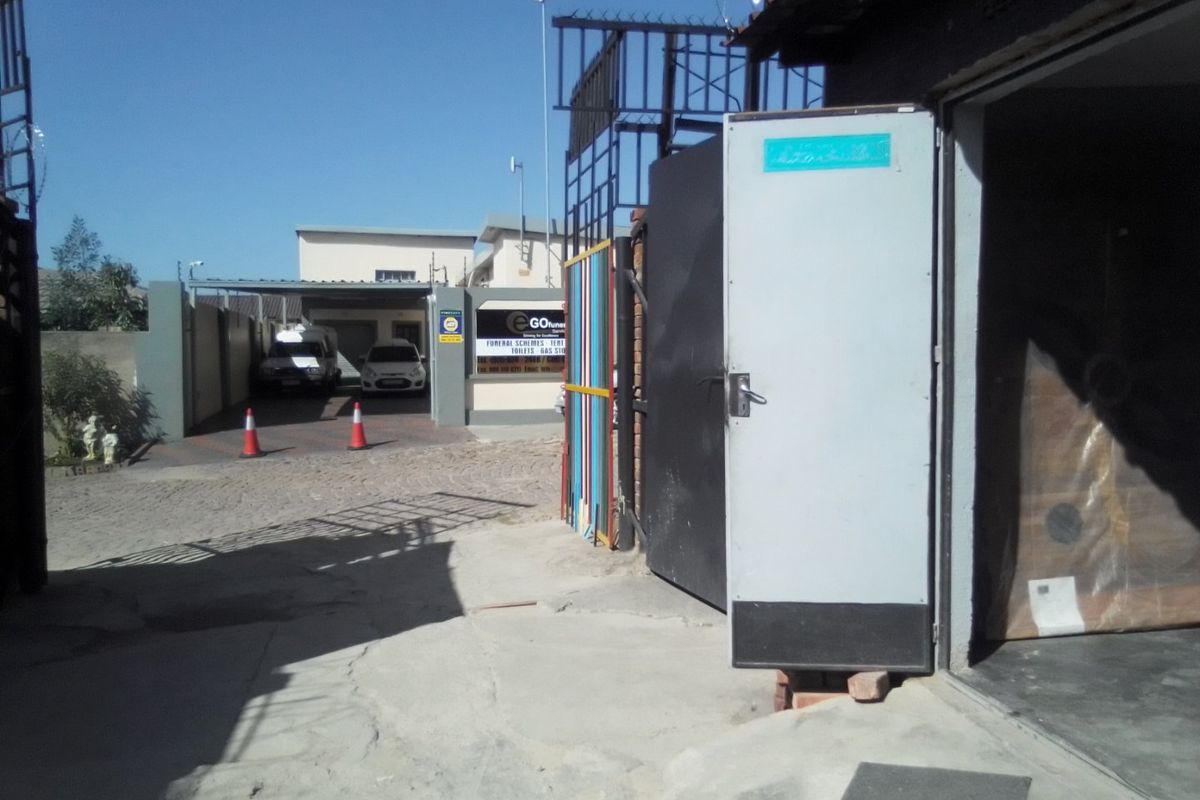 Commercial property entrance featuring a paved driveway, security gate, and perimeter fencing with security spikes.