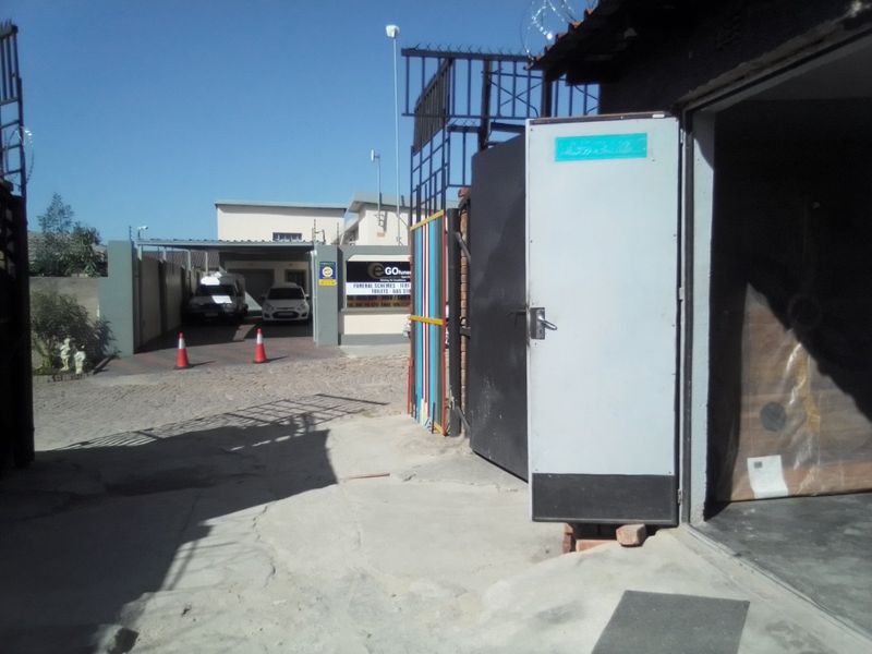 Commercial property entrance featuring a paved driveway, security gate, and perimeter fencing with security spikes.