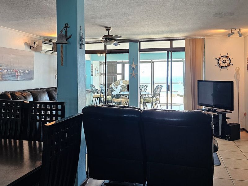 Open plan living and dining area featuring tiled floors, a ceiling fan, and large sliding glass doors leading to an outdoor balcony space.