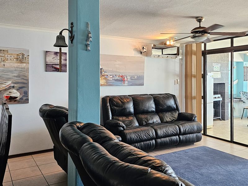 Open plan living area featuring tiled flooring, a ceiling fan, split-system air conditioning, and sliding glass doors leading to an outdoor space.