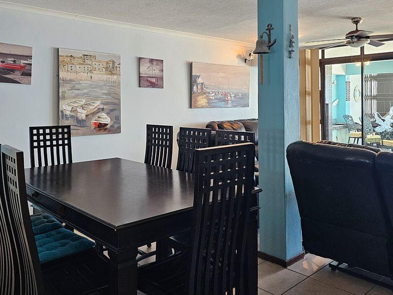 Open plan living and dining area featuring tiled flooring, a ceiling fan, and sliding glass doors leading to an outdoor balcony space.