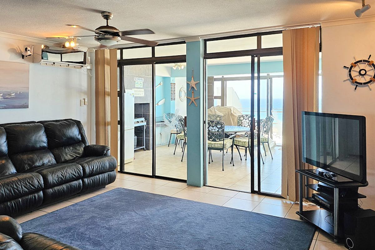 Spacious living room featuring tiled flooring, a ceiling fan, and large sliding glass doors that provide seamless access to the outdoor patio area.