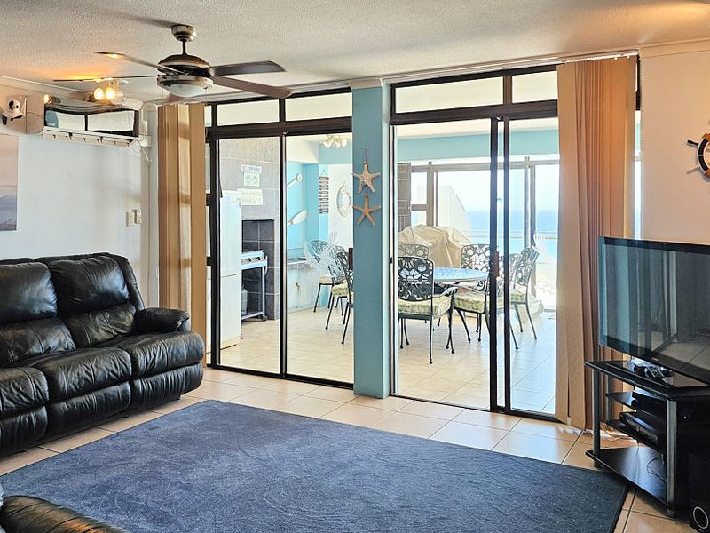 Spacious living room featuring tiled flooring, a ceiling fan, and large sliding glass doors that provide seamless access to the outdoor patio area.