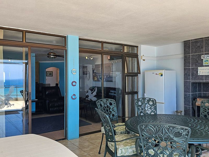 Covered balcony featuring tiled flooring, a built-in braai with tiled surround, and sliding glass doors providing access to the interior living area.