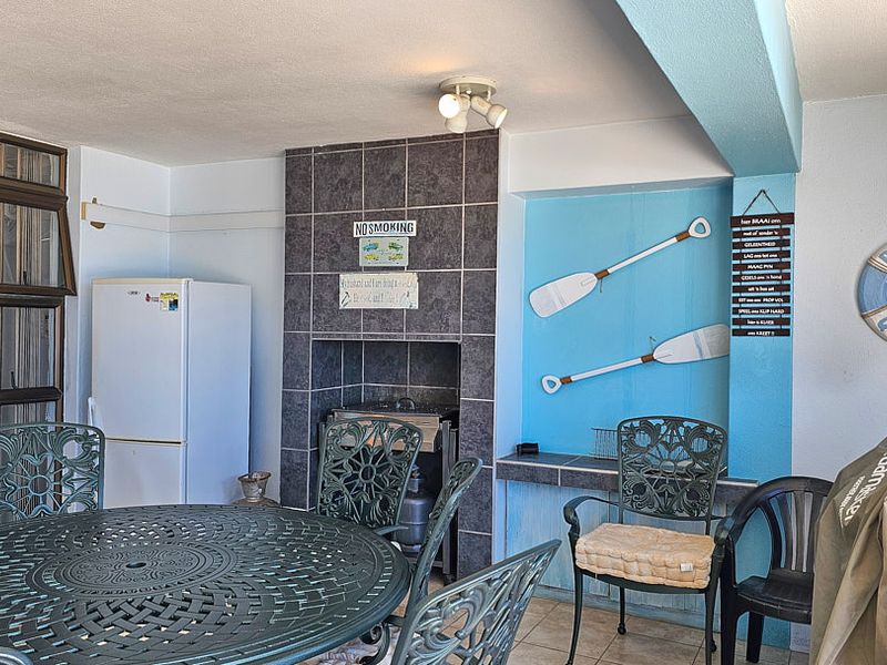 Covered patio area featuring a built-in braai with tiled surround, tiled flooring, and a built-in counter space, ideal for outdoor entertaining.