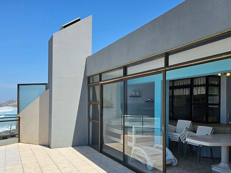 Spacious balcony featuring tiled flooring, metal balustrades, and large sliding glass doors offering expansive ocean views.