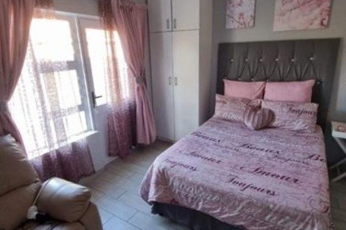 A well-maintained bedroom featuring tiled flooring, a built-in wardrobe, and large windows that provide ample natural light.