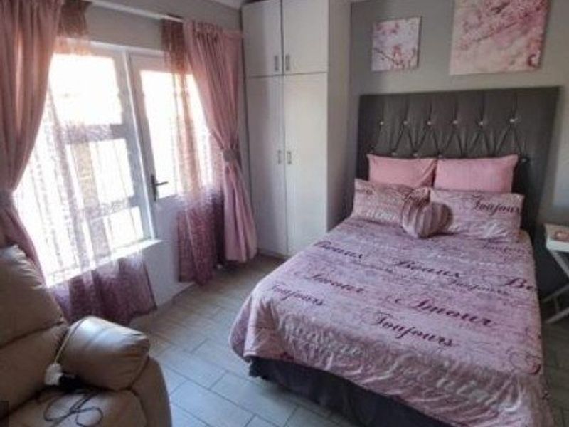 A well-maintained bedroom featuring tiled flooring, a built-in wardrobe, and large windows that provide ample natural light.