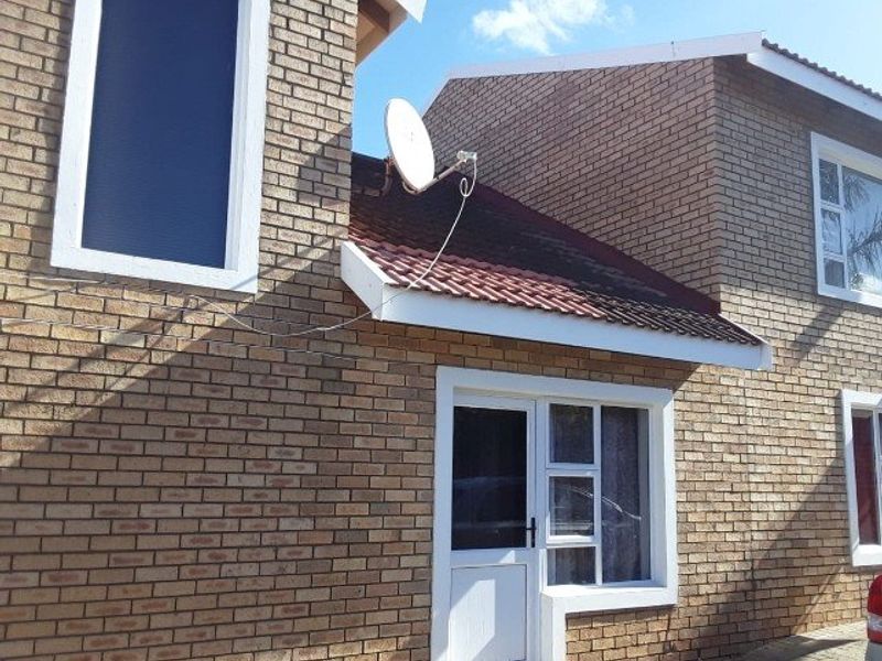 A view of the front facade featuring face brick construction, tiled roofing, and white uPVC window frames with a security entrance door.