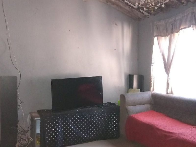 Living room featuring tiled flooring, an exposed corrugated roof structure, and a decorative chandelier, requiring cosmetic updates and electrical maintenance.