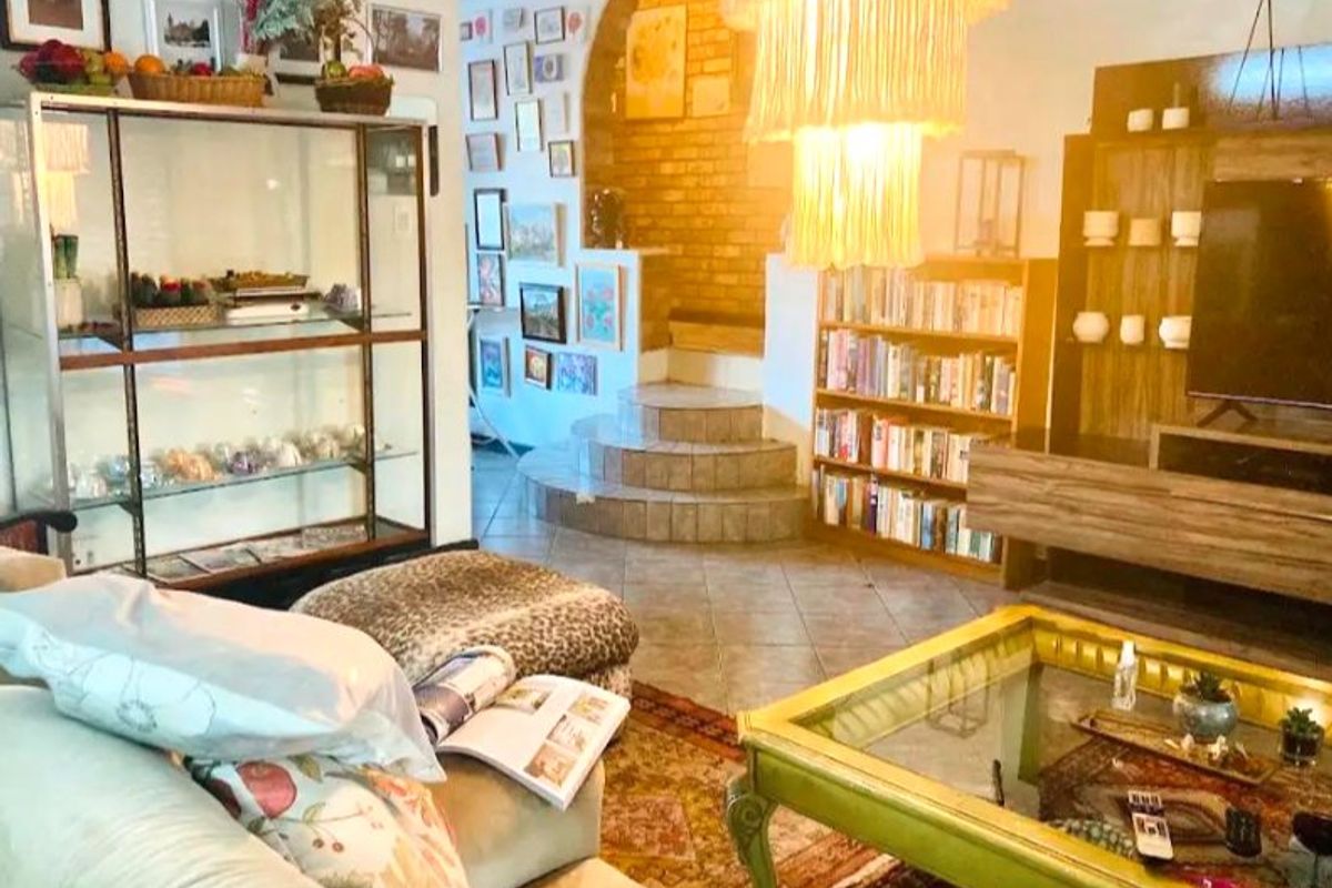 A living room featuring a brick accent wall, a tiled staircase, and ceramic flooring, offering a unique architectural layout with built-in shelving.