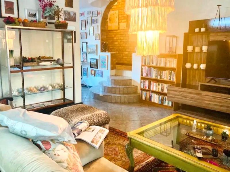 A living room featuring a brick accent wall, a tiled staircase, and ceramic flooring, offering a unique architectural layout with built-in shelving.