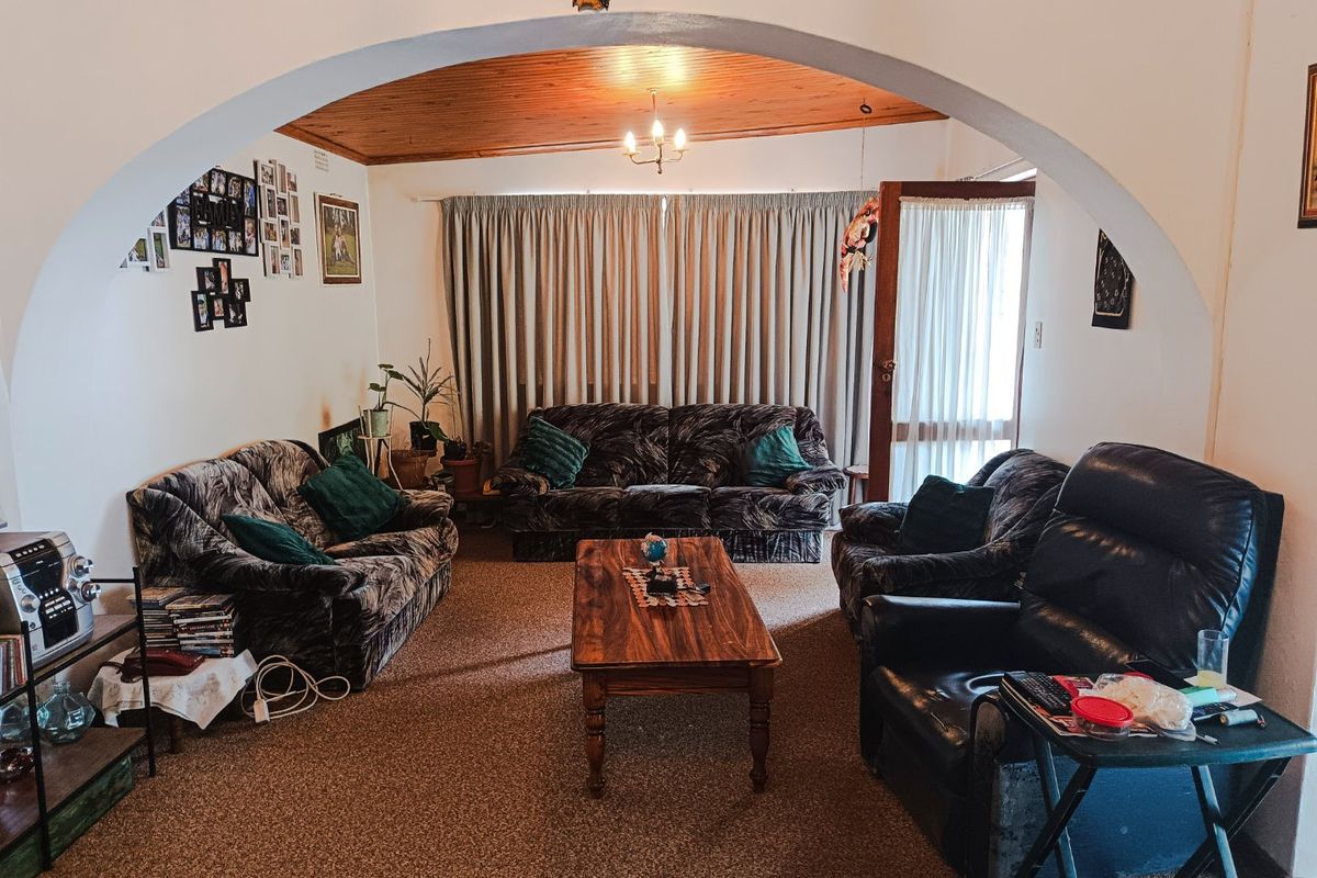 A cozy living room featuring a distinctive arched entryway, warm timber ceiling, and direct access to the outdoors through a sliding glass door.