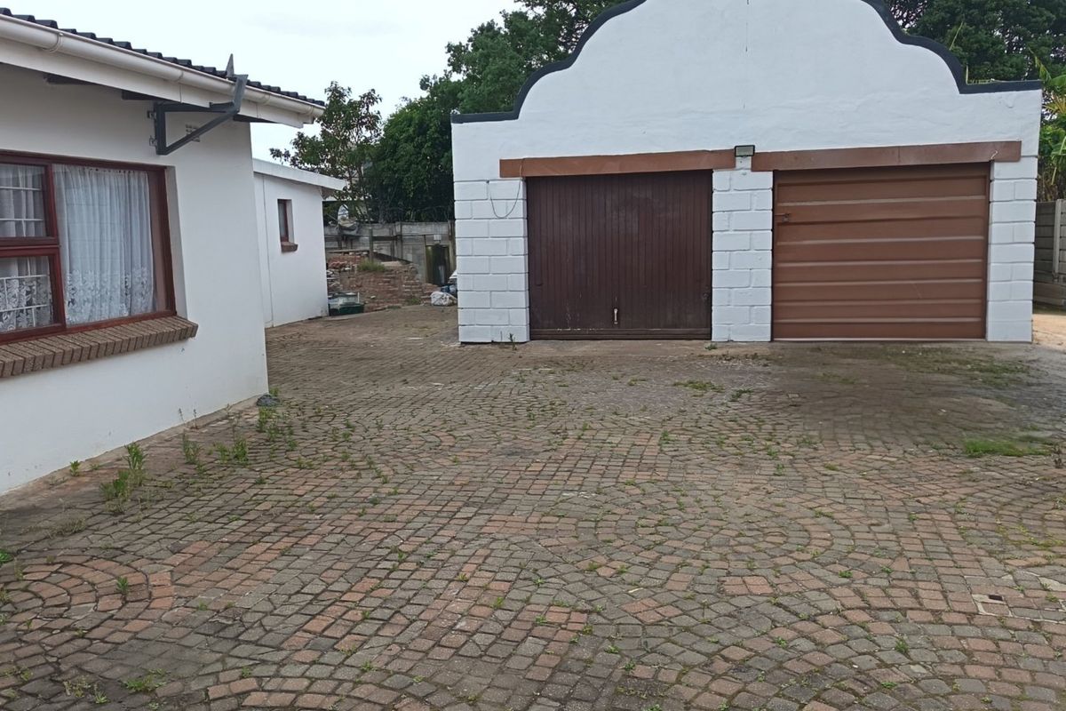 Rear exterior view featuring a double garage with a gabled roof and a paved driveway area.