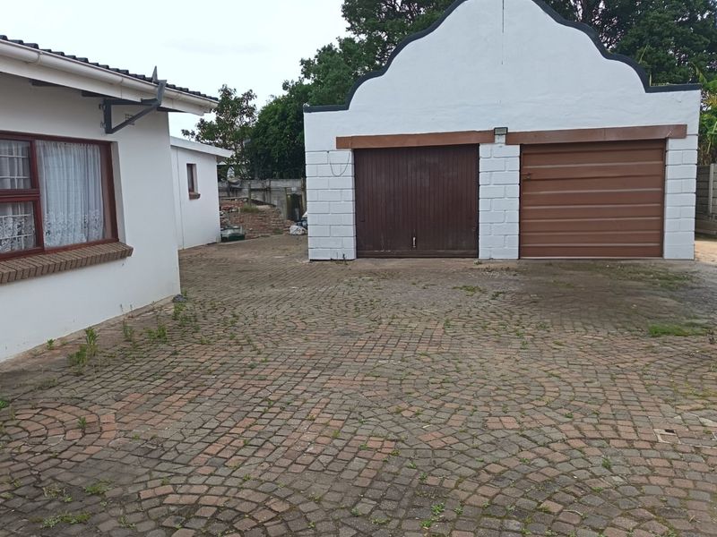 Rear exterior view featuring a double garage with a gabled roof and a paved driveway area.