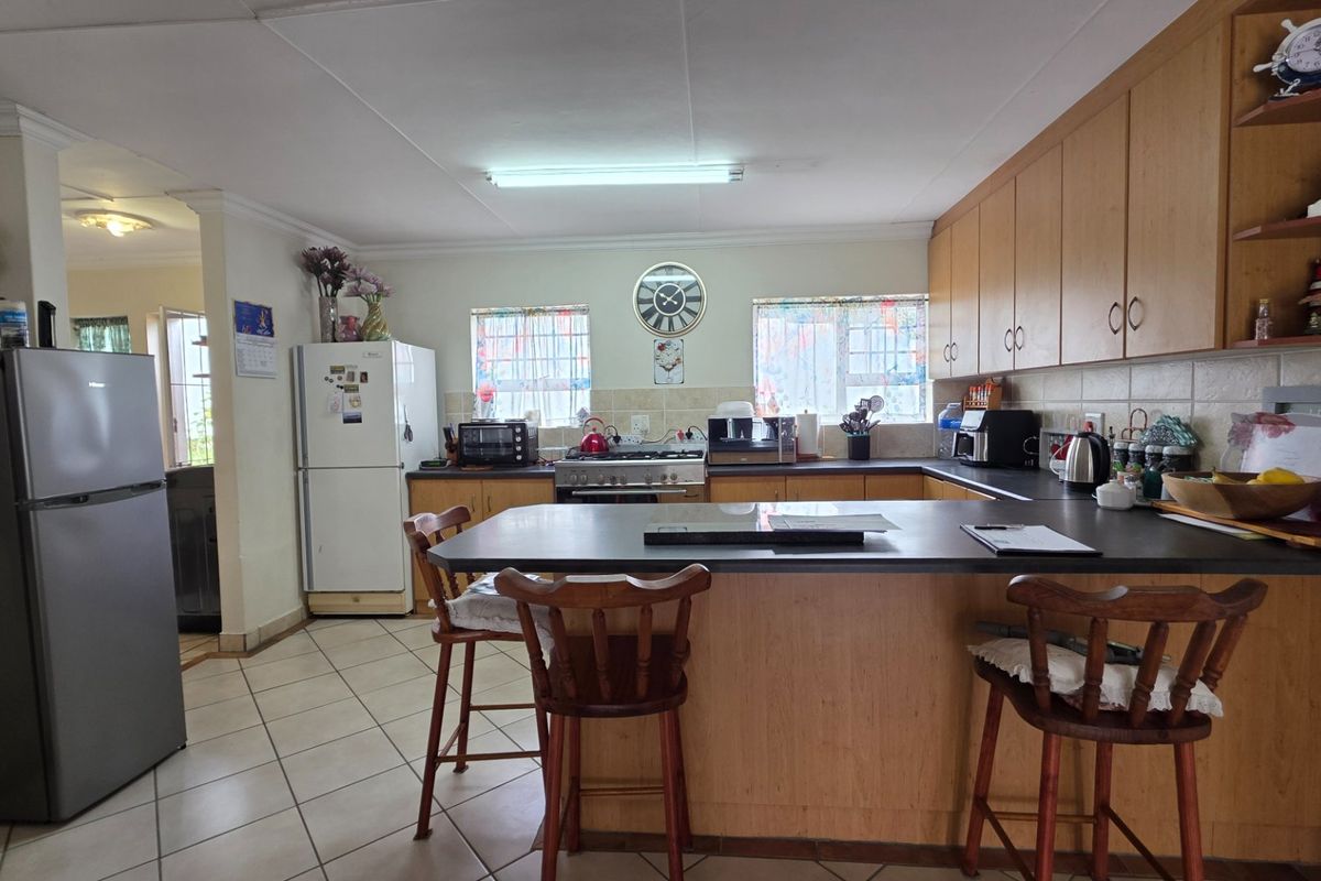 A functional kitchen featuring wooden cabinetry, laminate countertops, a gas stove, and a breakfast bar, with tiled flooring and backsplash throughout.
