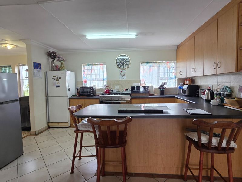 A functional kitchen featuring wooden cabinetry, laminate countertops, a gas stove, and a breakfast bar, with tiled flooring and backsplash throughout.