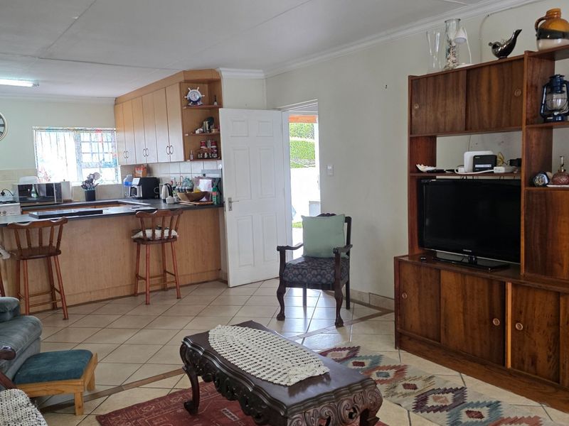 Open-plan living and kitchen area featuring tiled flooring, built-in cabinetry, and a central kitchen island, offering a functional and connected living space.
