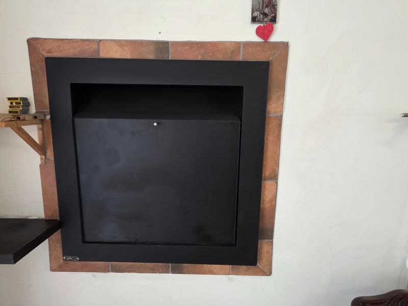 A living room featuring a built-in black metal fireplace with a decorative terracotta tiled surround.