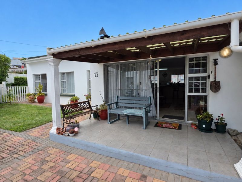 A covered patio area featuring tiled flooring, decorative columns, and a timber pergola, providing a functional outdoor space adjacent to the main entrance.
