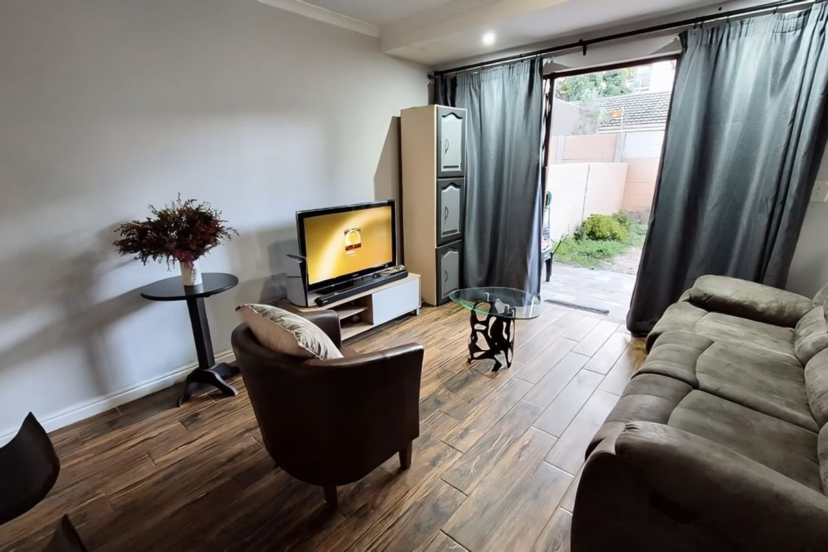 A living room featuring wood-look tile flooring and a sliding glass door providing direct access to the outdoor area.
