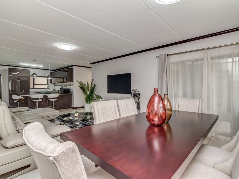 Spacious open-plan living and dining area featuring tiled flooring, modern kitchen cabinetry with an island, and seamless flow to the outdoor space.