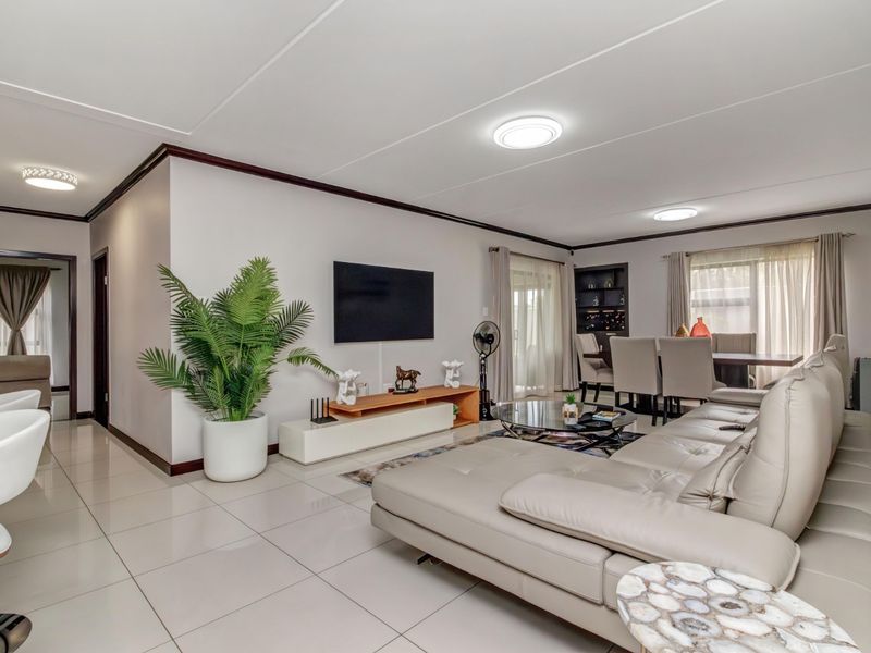 Spacious open-plan living and dining area featuring neutral tiled flooring, modern ceiling lighting, and direct access to outdoor space through sliding glass doors.