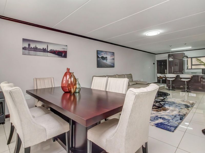 Spacious open-plan living and dining area featuring polished tiled flooring, modern kitchen cabinetry with an island, and contemporary pendant lighting.