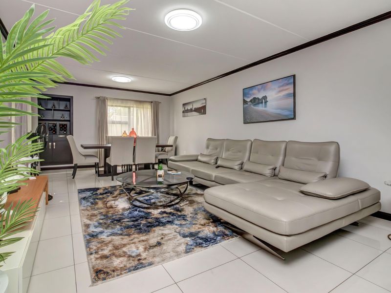 Spacious open-plan living and dining area featuring polished tiled flooring, neutral walls, and a built-in display cabinet, creating a bright and functional living space.