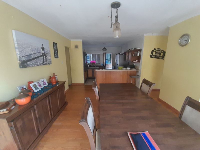Open plan dining and kitchen area featuring wooden flooring, cabinetry, and a central kitchen island, offering a functional layout for daily living.