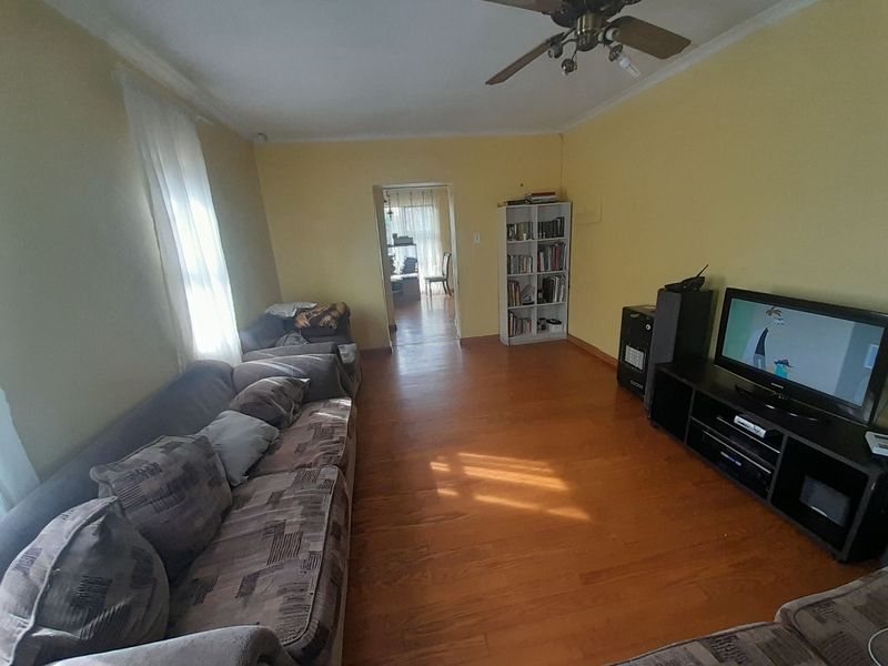 A living room featuring hardwood flooring, cove molding, and a ceiling fan, providing a functional and comfortable space.