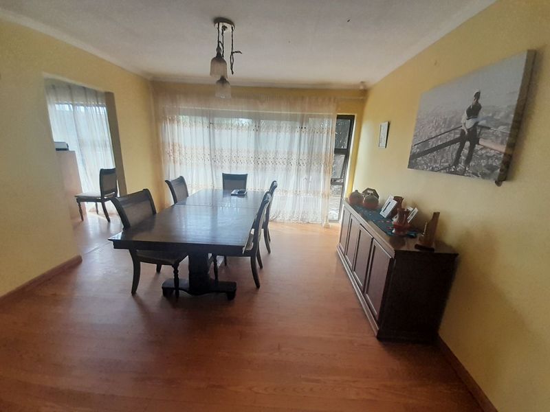 A dining room featuring laminate flooring, a large sliding glass door providing natural light, and a central pendant light fixture.