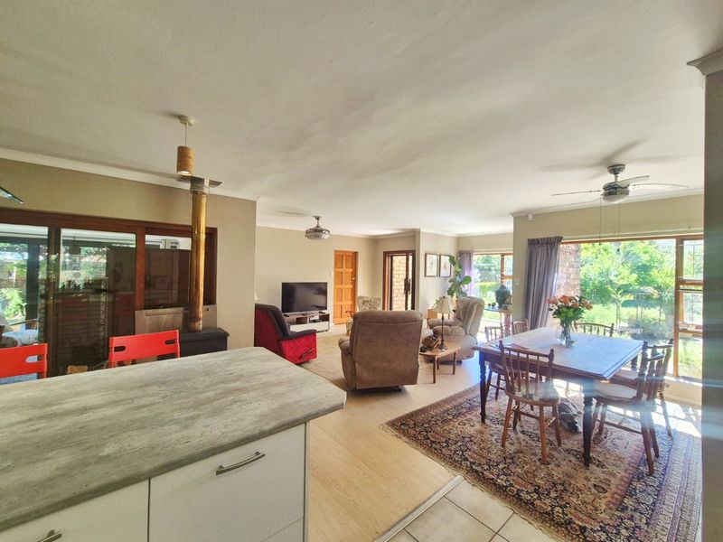 Spacious open-plan living and dining area featuring laminate flooring, a wood-burning fireplace, and large sliding doors providing ample natural light and garden access.