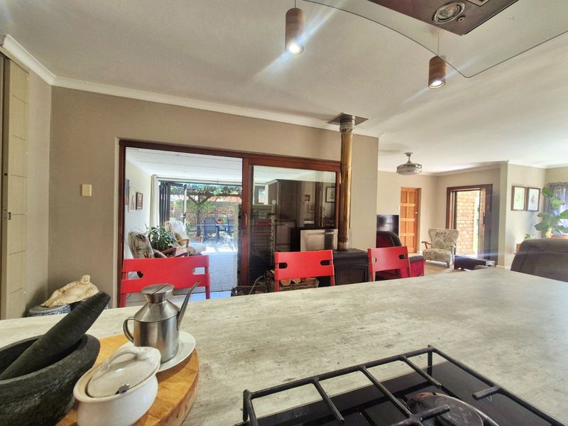 Open-plan living area featuring a central kitchen island with a built-in hob, a cozy fireplace, and seamless access to the outdoor patio.