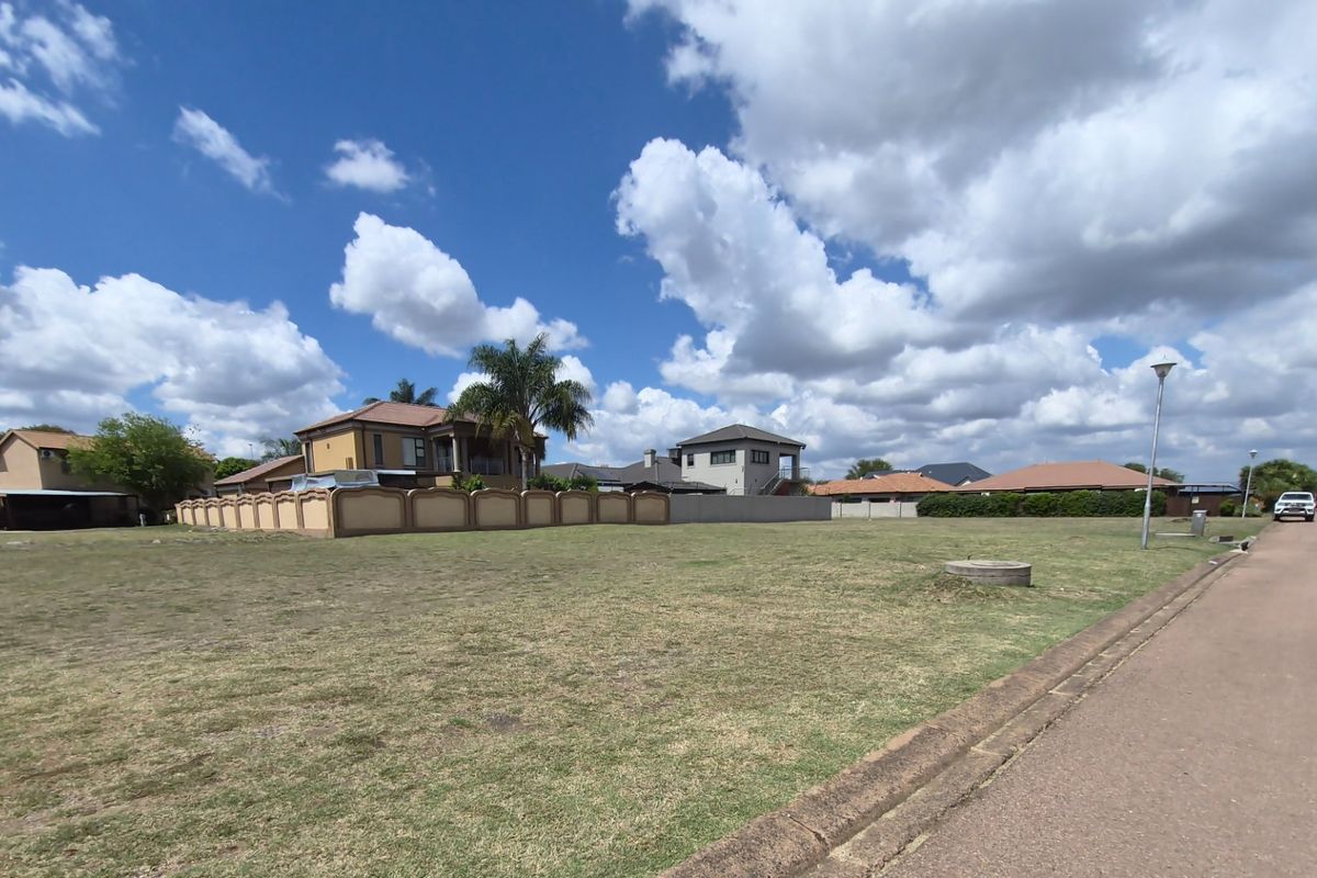 A vacant residential plot of land featuring a grass lawn, adjacent to a paved street with curb infrastructure.