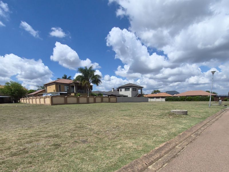 A vacant residential plot of land featuring a grass lawn, adjacent to a paved street with curb infrastructure.