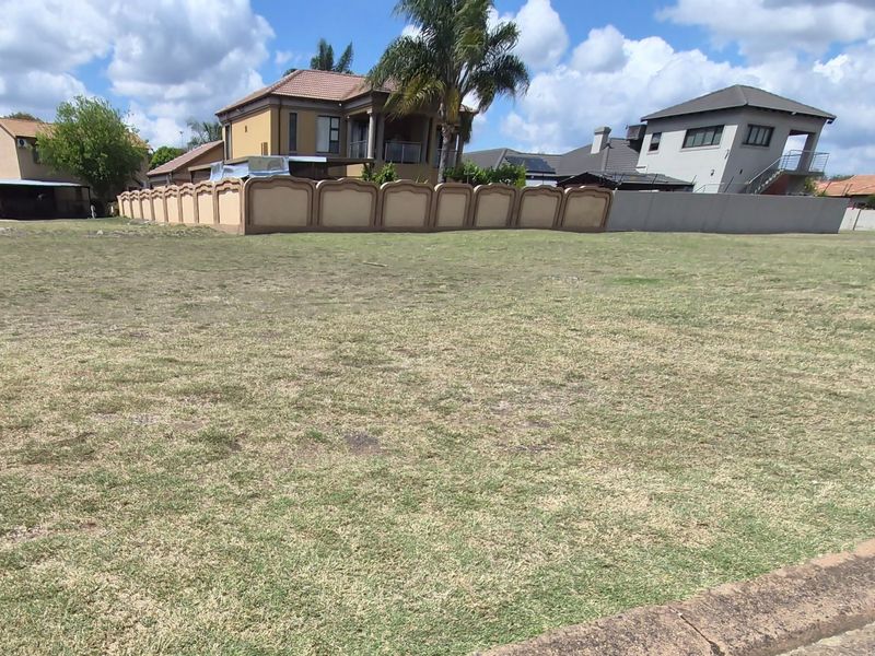 A vacant residential plot featuring a grass lawn and established boundary wall, situated in a developed neighborhood.