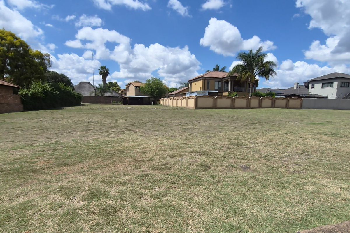 A spacious, level residential vacant land plot featuring a grass lawn and established perimeter boundary walls in a suburban neighborhood.