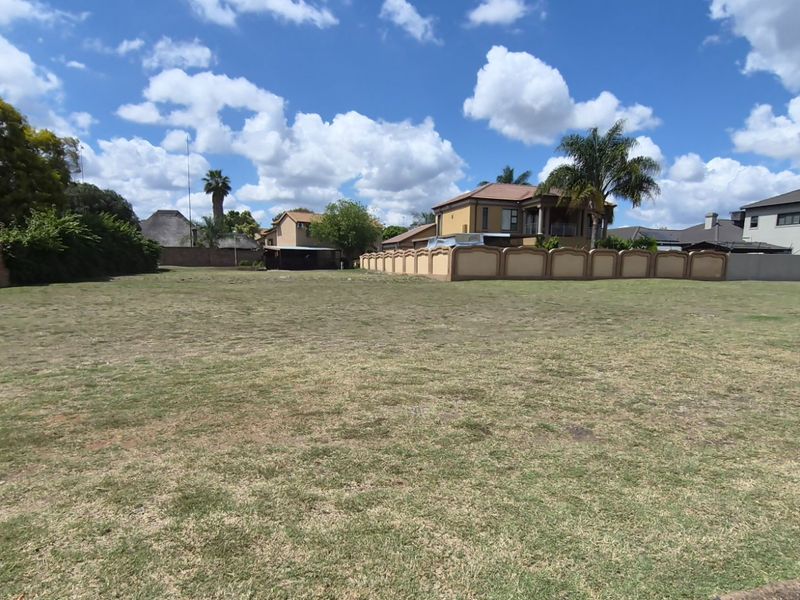 A spacious, level residential vacant land plot featuring a grass lawn and established perimeter boundary walls in a suburban neighborhood.